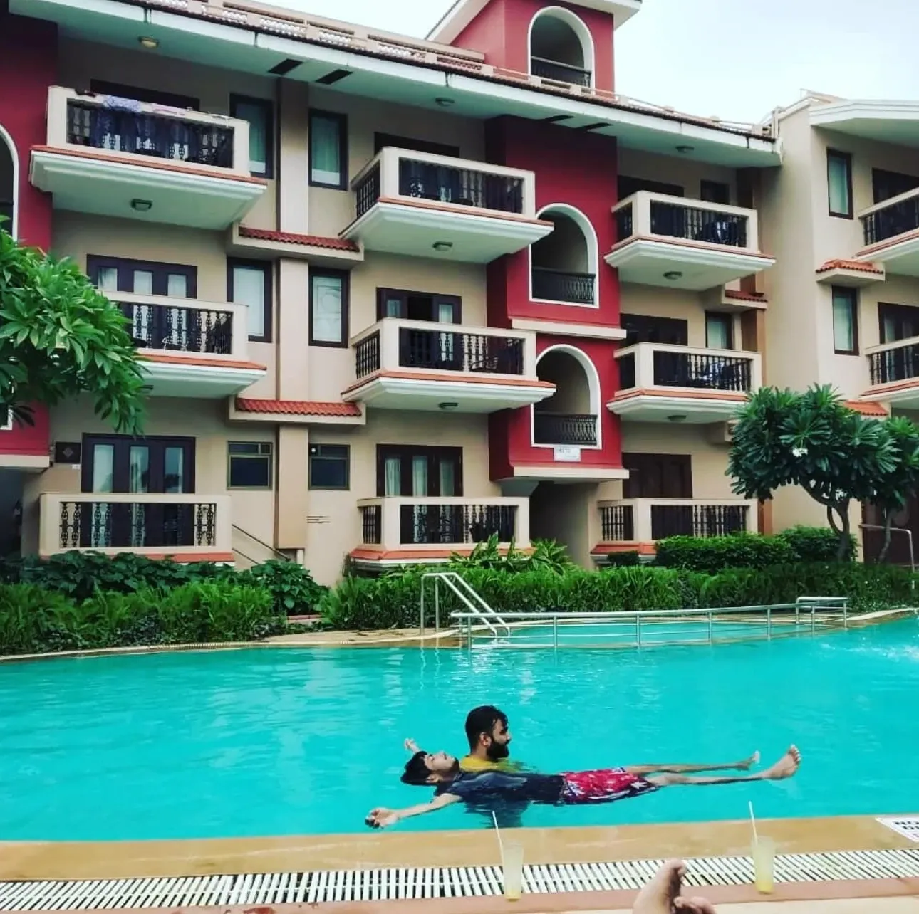 Friends floating in a resort pool in Goa