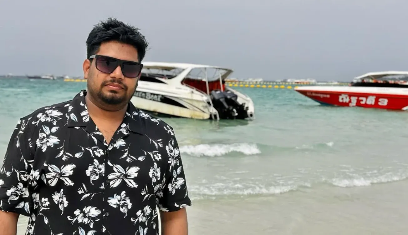 Rahul on a beach with speedboats behind
